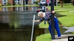 A resident measures the depth of stormwater in a flooded street in Pooler, Georgia, Aug. 7, 2024. 