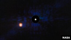 The exoplanet Epsilon Indi Ab is seen with NASA’s Webb Space Telescope’s MIRI (Mid-Infrared Instrument). A star symbol marks the host star Epsilon Indi A, whose light has been blocked by a coronagraph, resulting in the dark circle marked with a dashed white line. 