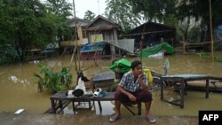 ရေကြီးနေတဲ့ ပဲခူးမြို့အတွင်း ရေမြုပ်သွားတဲ့နေအိမ်ရှေ့မှာထိုင်နေသူတဦး (အောက်တိုဘာ ၁၀၊ ၂၀၂၃)