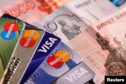Gambar ilustrasi - Kartu kredit MasterCard, VISA dan Maestro dengan uang kertas rubel Rusia, 9 Juni 2016. (REUTERS/Maxim Zmeyev)