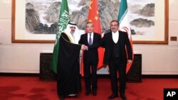 FILE - Ali Shamkhani, the secretary of Iran's Supreme National Security Council, right, shakes hands with Saudi national security adviser Musaad bin Mohammed al-Aiban, left, as Wang Yi, China's most senior diplomat, looks on, Beijing, March 11, 2023. 