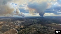 This handout image released by Alberta Wildfire shows smoke columns going in multiple directions due to shifting winds in Fort McMurray Forest Area, Alberta, Canada, on May 13, 2024. 
