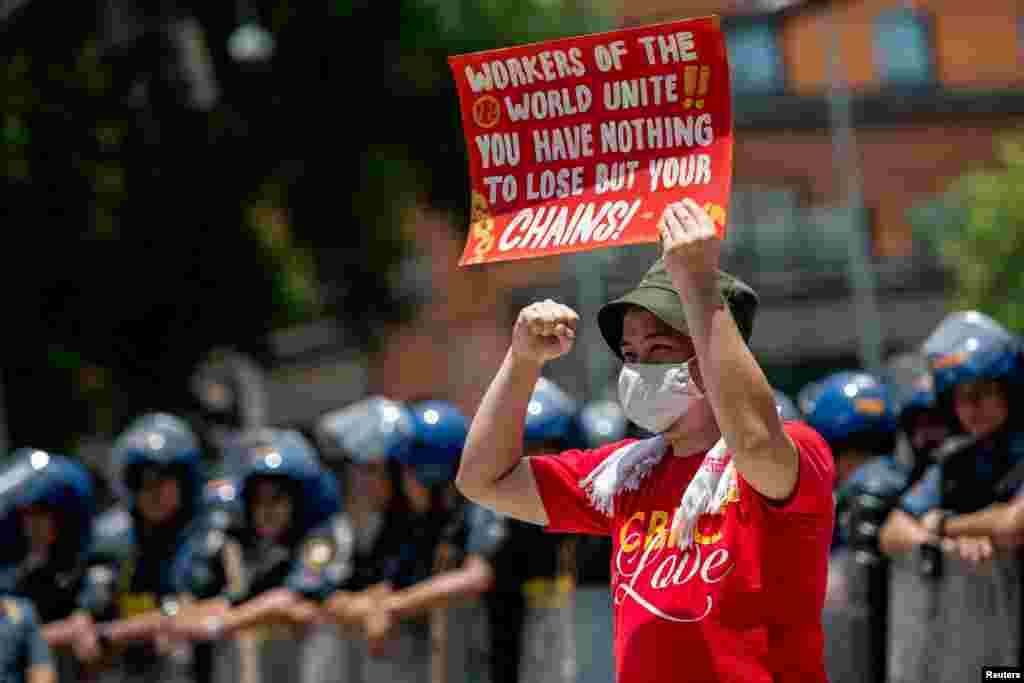 A labor activist holds a placard as he raises his fist, during a Labor Day protest near the U.S. Embassy, in Manila, Philippines.