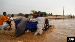 People push a vehicle through muddy flood water along a street, following torrential rain in Saqqai near Omdurman, Sudan, Aug. 5, 2023. 