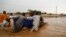 People push a vehicle through muddy flood water along a street, following torrential rain in Saqqai near Omdurman, Sudan, Aug. 5, 2023. 