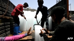 Workers stack ice blocks at a market amid a heat wave in New Delhi on May 30, 2024.