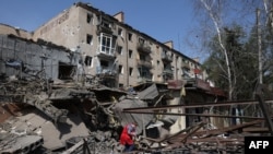 一名婦女站在烏克蘭頓內茨克州科斯特揚蒂尼夫卡鎮被炸毀的建築廢墟中。 （2024年4月11日）