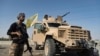 FILE - A U.S.-backed Syrian Democratic Forces fighter stands next to an armored vehicle in the eastern countryside of Deir el-Zour, Syria, Sept. 4, 2023. New attacks between SDF fighters and Iran-backed Syrian government forces were launched in the area Sept. 20, 2024.