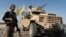 FILE - A U.S.-backed Syrian Democratic Forces fighter stands next to an armored vehicle at al-Sabha town in the eastern countryside of Deir el-Zour, Syria, Sept. 4, 2023.