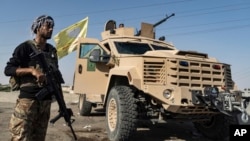 A U.S.-backed Syrian Democratic Forces fighter stands next to an armored vehicle at al-Sabha town in the eastern countryside of Deir el-Zour, Syria, Sept. 4, 2023.