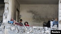 22일 가자지구 남부 라파에서 이스라엘 군의 공습이 계속되는 가운데 팔레스타인 어린이들이 이스라엘의 공습으로 파괴된 집에 앉아있다.