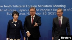 FILE - Menteri Luar Negeri Korea Selatan Park Jin (tengah) mendampingi Menteri Luar Negeri China Wang Yi dan Menteri Luar Negeri Jepang Yoko Kamikawa menjelang pertemuan menlu trilateral ke-10 di Busan, Korea Selatan, 26 November 2023. (Ahn Young-joon/Pool via REUTERS)