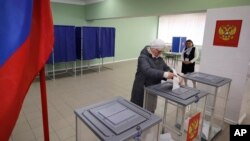 A woman votes at a polling station during a presidential election in Makiivka, Russian-controlled Donetsk region, eastern Ukraine, March 15, 2024. People in Moscow-controlled Ukrainian regions are voting in Russia's presidential election.