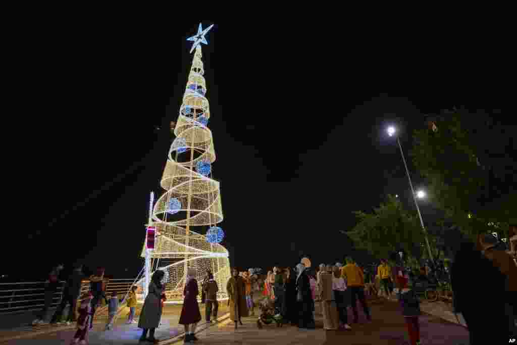 Iraquianos reúnem-se para celebrar o Ano Novo à volta de uma árvore de Natal em Bagdade, Iraque, a 31 de dezembro de 2023.