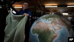 Peter Bellerby, the founder of Bellerby & Co. Globemakers, covers a globe at his studio in London, Britain, Feb. 27, 2024.