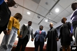 Rev. Gina Stewart, third from right, holds hands with students and faculty of Howard University before church service at Rankin Chapel, April 7, 2024, in Washington.