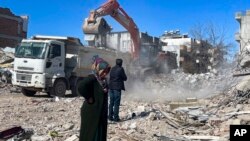 Taha Erdem's mother, Zeliha Erdem, and father, Ali Erdem, stand next to the debris from the building where Tahan was trapped after the earthquake of Feb. 6, in Adiyaman, Turkey, Feb. 17, 2023.