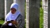 Seorang penyintas Pembantaian Srebenica 1995 duduk dan berdoa di antara sejumlah pusara korban pembantaian yang terletak di desa Potocari, dekat Srebenica, Bosnia, pada 11 Juli 2024. (Foto: AFP/Elvis Barukcic)