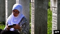 Seorang penyintas Pembantaian Srebenica 1995 duduk dan berdoa di antara sejumlah pusara korban pembantaian yang terletak di desa Potocari, dekat Srebenica, Bosnia, pada 11 Juli 2024. (Foto: AFP/Elvis Barukcic)