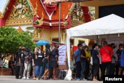 Voters stand in a queue to cast their ballot to vote in the general election at a polling station in Bangkok, Thailand, May 14, 2023.