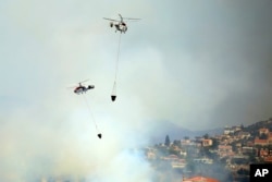 Two helicopters operate over a fire in Apesia, a semi-mountainous village near Limassol, southwestern Cyprus, Aug. 7, 2023.