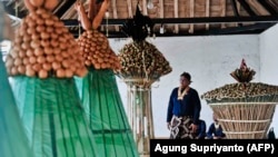 Para abdi dalem Sultan Yogyakarta yang mengikuti upacara Tumplak Wajik menyiapkan Gunungan (kiri) berbentuk gunung berisi aneka makanan di Keraton Keraton Yogyakarta. (Foto: AFP/Agung Supriyanto)