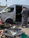 Pakistani investigators examine a damaged van at the site of a suicide attack in Karachi, Pakistan, April 19, 2024. 