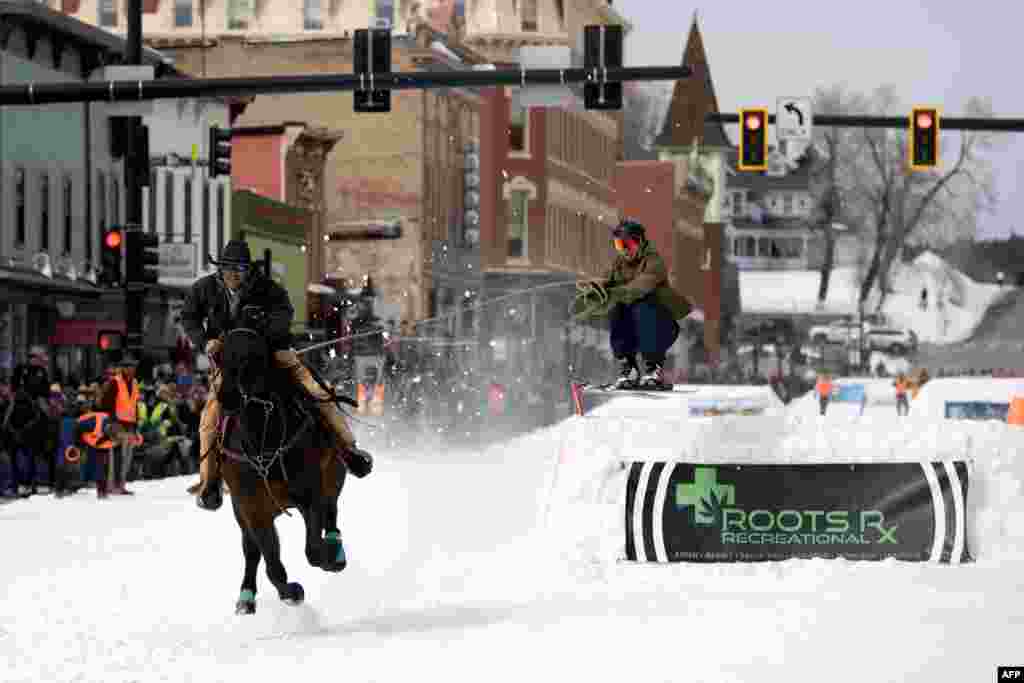 Rider Carl Gomez races down Harrison Avenue as skier Ben Southworth airs out a jump during the 75th annual Leadville Ski Joring weekend competition in Leadville, Colorado, March 4, 2023.