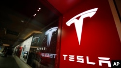 FILE - A sign bearing the Tesla company logo is displayed outside a Tesla store in Cherry Creek Mall in Denver, Colorado, Feb. 9, 2019.