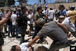 Israeli police officers separate Israelis and Palestinians in front of the Damascus Gate of Jerusalem's Old City shortly before a march through the area by Jewish nationalists in Jerusalem Day, June 5, 2024.