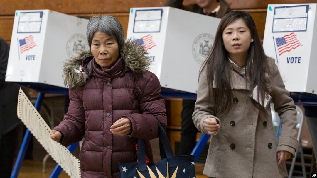 Seorang pemilih (kiri), membawa surat suaranya, sambil dibantu oleh penerjemah Ping Chan, di lingkungan Sunset Park wilayah Brooklyn, New York, Selasa, 8 November 2016. (AP/Mark Lennihan)