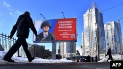 A man walks by a billboard depicting a Russian soldier and a slogan reading 'Thank you to the Heroes of Russia!' in a street of Saint Petersburg, March 7, 2023.