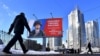 Seorang pria berjalan melewati papan reklame yang menggambarkan tentara Rusia dan slogan bertuliskan 'Terima kasih kepada Pahlawan Rusia!' di jalan Saint Petersburg, 7 Maret 2023.