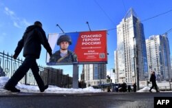 A man walks by a billboard depicting a Russian soldier and a slogan reading 'Thank you to the Heroes of Russia!' in a street of Saint Petersburg, March 7, 2023.