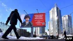 Seorang pria berjalan melewati papan reklame yang menggambarkan tentara Rusia dan slogan bertuliskan 'Terima kasih kepada Pahlawan Rusia!' di jalan Saint Petersburg, 7 Maret 2023.