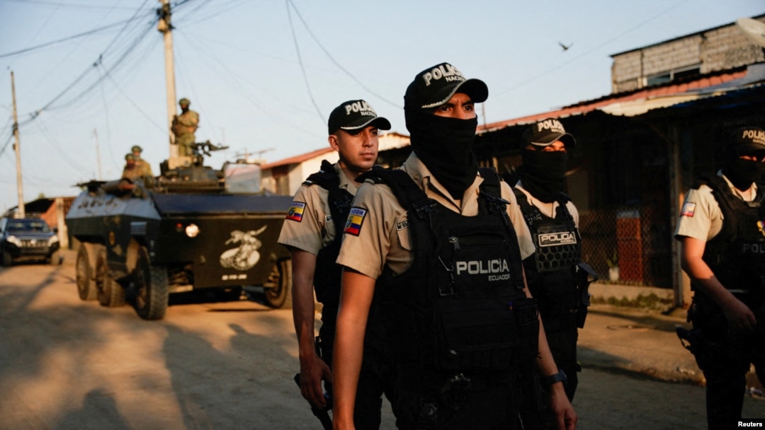 ARCHIVO - Oficiales de policía caminan delante de un vehículo militar blindado mientras participan en una operación conjunta militar y policial en el barrio Socio Vivienda, en Guayaquil, Ecuador, 26 de marzo de 2024.