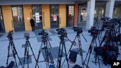 TV cameras are seen during a stakeout in front of the High Court in Belgrade, Serbia, Jan. 29, 2024. A trial started Monday for the parents of a teenager who is accused of killing 10 people and injuring six in a mass shooting at his school last May.