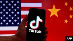 显示美国国旗和中国国旗的背景映衬着一台带有TikTok标识的苹果公司iPhone手机。（2023年3月16日）