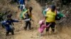 FILE - A woman lifts a child from a muddied path as Ecuadorian migrants walk across the Darien Gap from Colombia into Panama, hoping to reach the U.S., on Oct. 15, 2022.