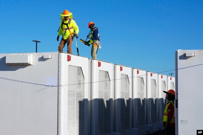 FILE - Workers do checks on battery storage pods at Orsted's Eleven Mile Solar Center lithium-ion battery storage energy facility Thursday, Feb. 29, 2024, in Coolidge, Ariz. (AP Photo/Ross D. Franklin)