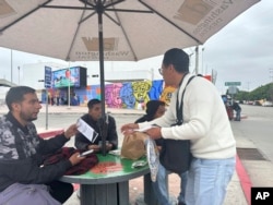 Hugo Lopez of Al Otro Lado advocacy group hands a pamphlet to Antonio Cortes, a Mexican man who was deported from the U.S. to Tijuana, Mexico, on June 11, 2024.