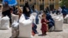 FILE - Afghan women receive food rations distributed by a humanitarian aid group, in Kabul, Afghanistan, May 28, 2023.