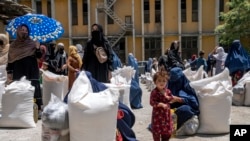 FILE - Afghan women receive food rations distributed by a humanitarian aid group, in Kabul, Afghanistan, May 28, 2023. A U.N. survey found 80% of women in Afghanistan reported a drop in their ability to undertake income-generating activities under the Taliban.