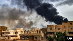 Un entrepôt de bois en feu dans le sud de Khartoum, au milieu des combats. (Photo de l'AFP)