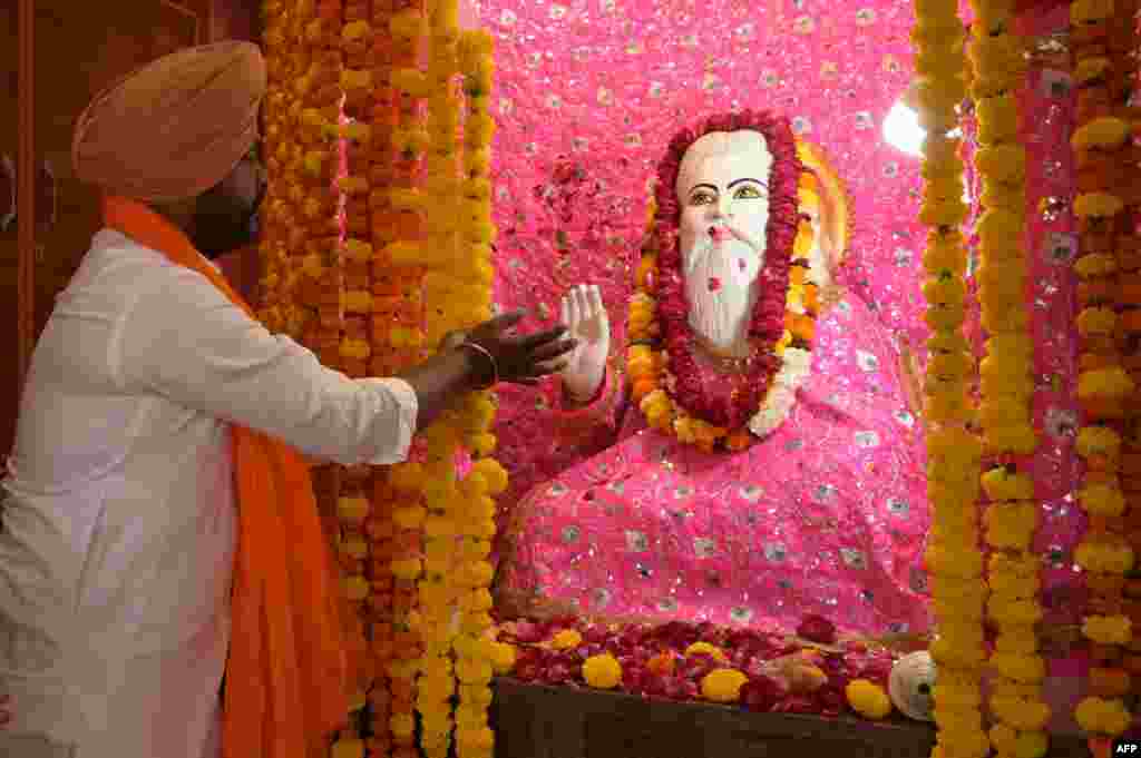 A devotee pays his respect to an idol of the Hindu deity Valmiki on the eve of "Valmiki Jayanti," commemorating his birth anniversary at a temple in Amritsar, India.