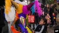 Seorang anak memukul piñata di acara "posada" jalanan di Mexico City, Jumat, 22 Desember 2023. Posada adalah acara tradisi pada bulan Desember sebanyak 9 kali hingga malam Natal, mewakili tempat yang disinggahi Yusuf dan Bunda Maria ketika mencari tempat melahirkan bayi Yesus.