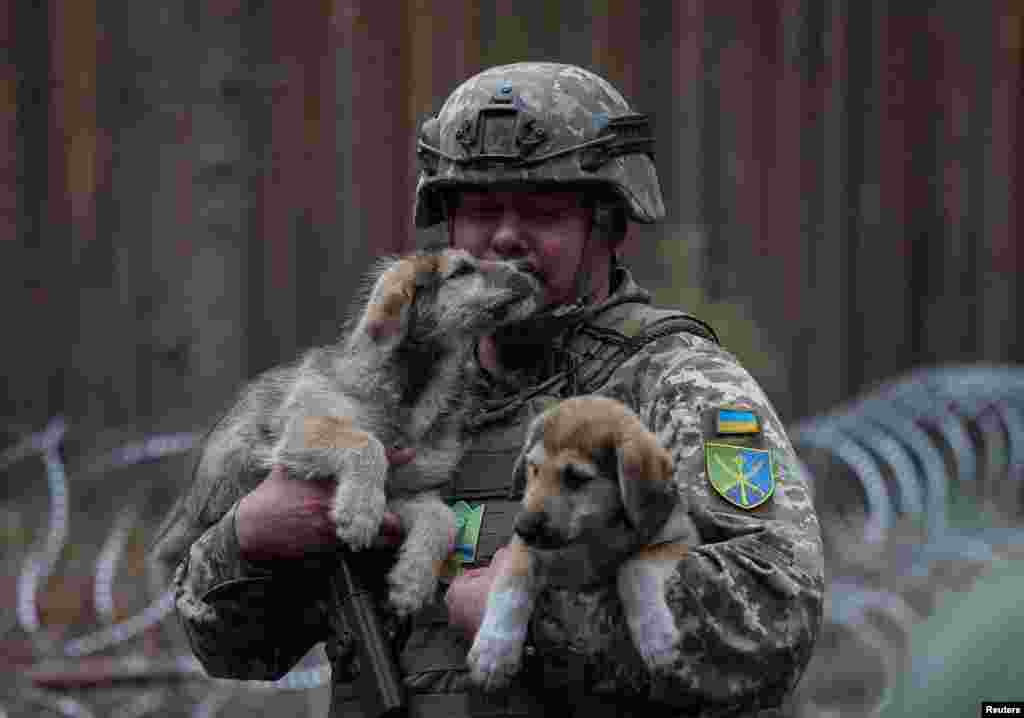Commander of the Joint Forces of the Armed Forces of Ukraine Serhiy Nayev holds puppies as he visits at positions near the border with Belarus in the Zhytomyr region of Ukraine, Sept. 20, 2023.