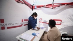 FILE - Gladys Rara undergoes screening before being tested for tuberculosis at a mobile clinic in Gugulethu township near Cape Town, South Africa, March 26, 2021. 