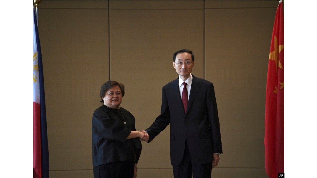 Theresa Lazaro, kiri, Wakil Menteri Luar Negeri Filipina untuk Hubungan Bilateral dan Urusan Asia Departemen Luar Negeri, berjabat tangan dengan Sun Weidong, Wakil Menteri Luar Negeri China, sebelum dimulainya pertemuan di Manila, Kamis, 23 Maret 2023. (Foto: via AP)