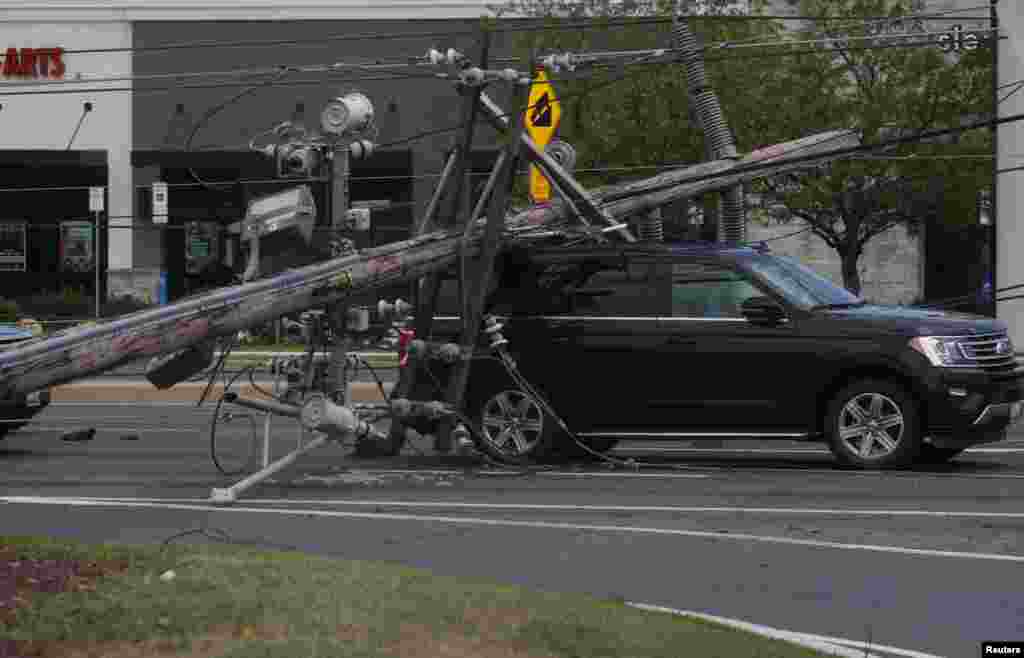 A downed power line falls on an SUV the day after a powerful storm swept the region along Baltimore Blvd in Westminster, Maryland, Aug. 8, 2023.